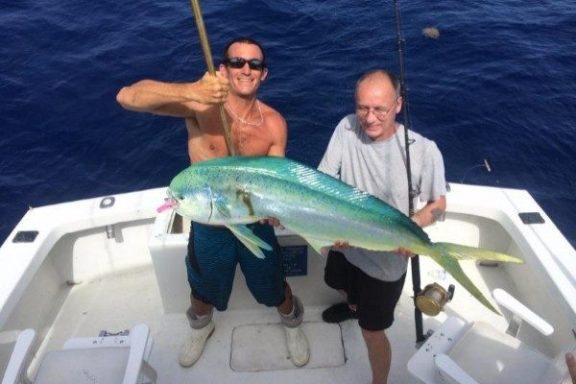 a man holding a fish on a boat in the water